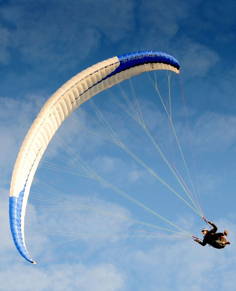 Hombre volando en las alturas, tir&aacute;ndose de parapente